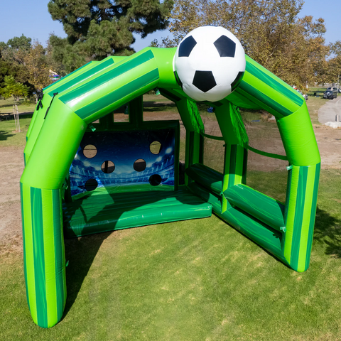 Large green soccer game with soccer ball on top in a field on a sunny day.
