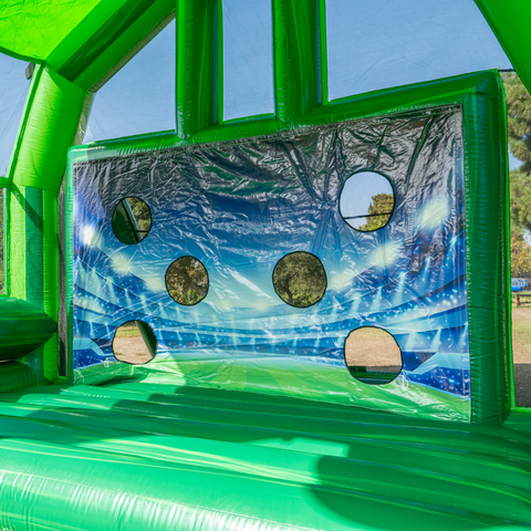 Inside of a green inflatable soccer game with a blue and white mesh with holes to aim for. 
