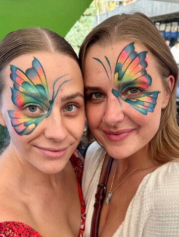 Smiling child with a butterfly face paint design created by a professional artist at a party.