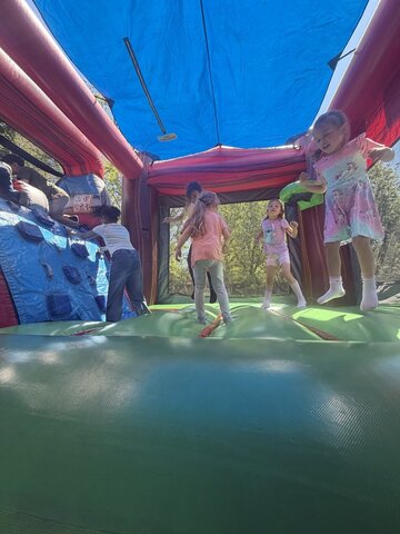 Three young girls playing inside a Disney princess-themed inflatable bounce house