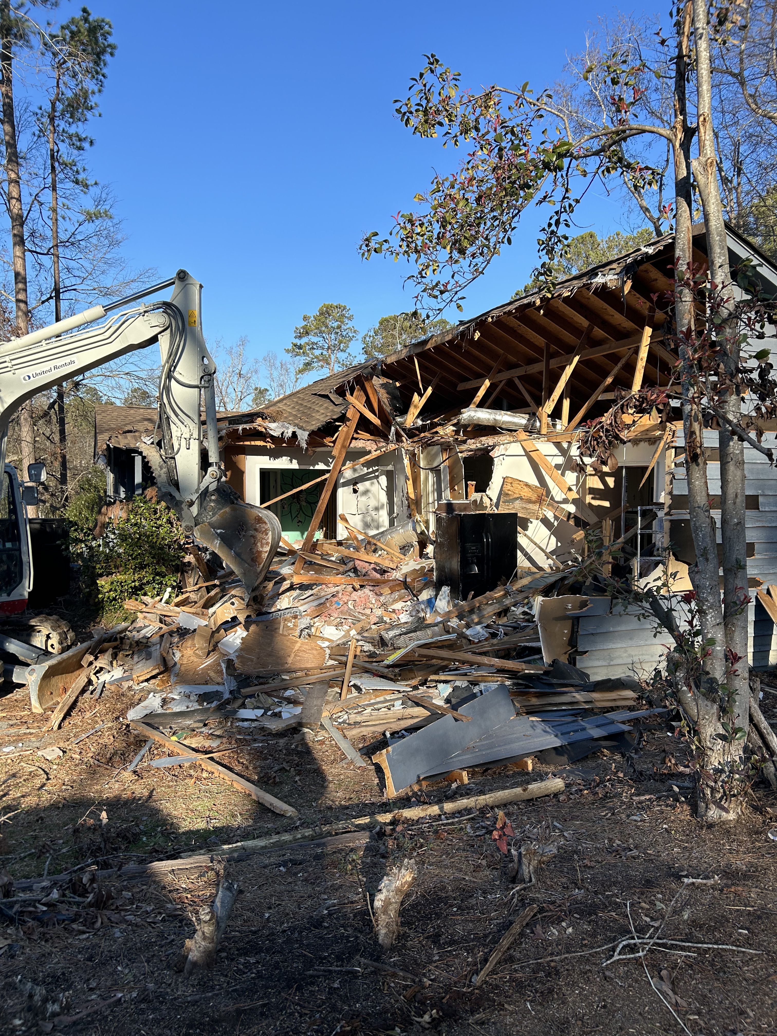 Junk Empire excavator demolishing house with debris scattered