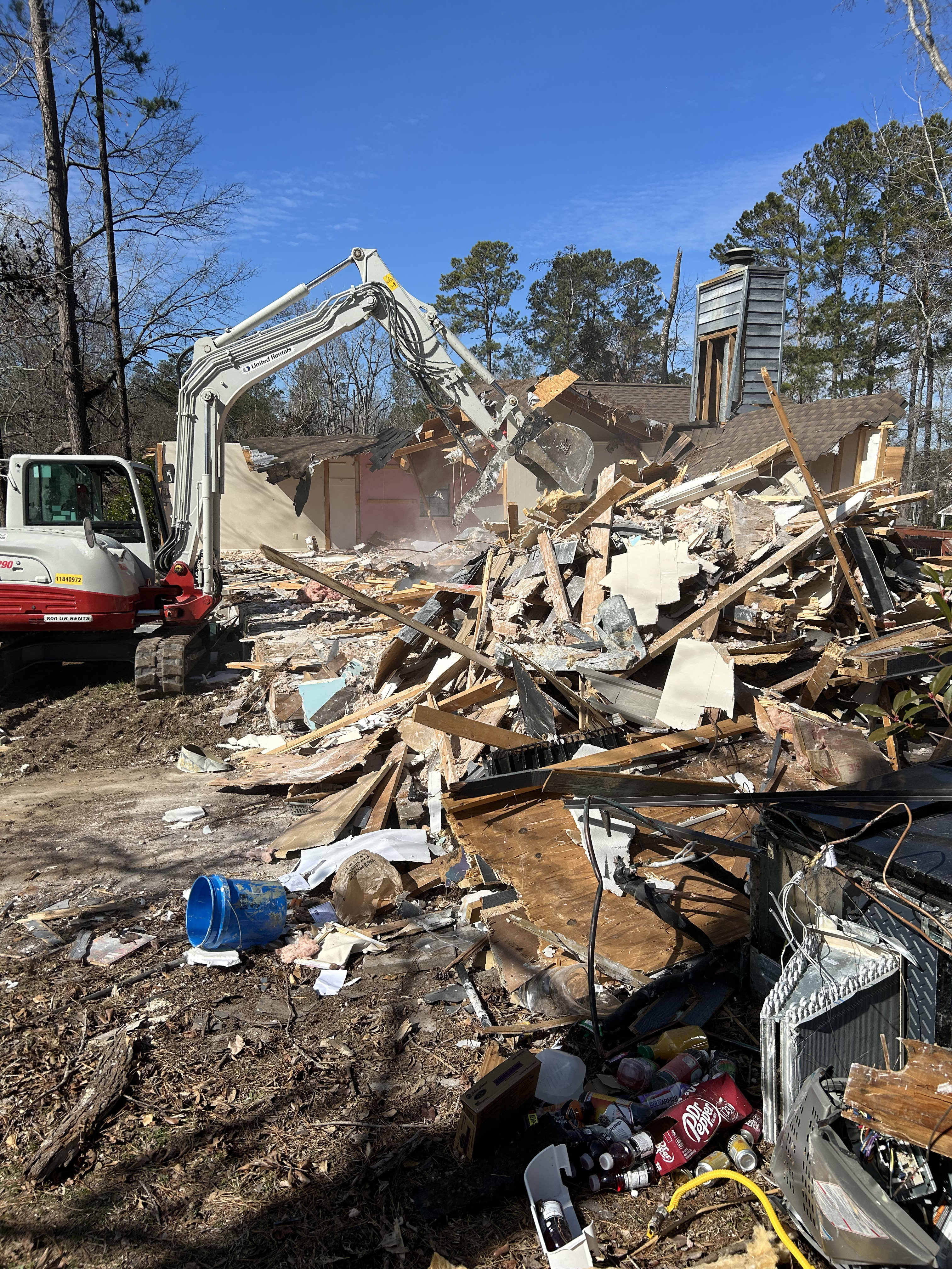 Junk Empire excavator tearing down house with rubble and debris