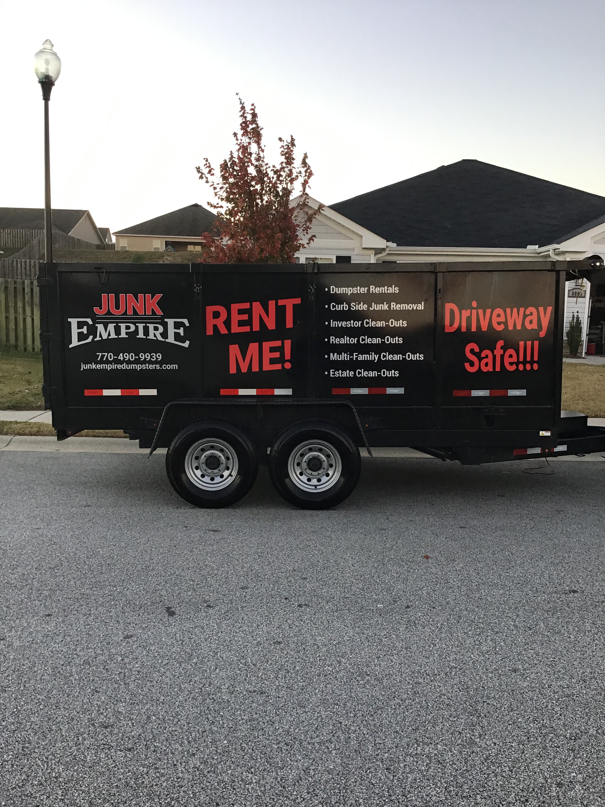 Junk Empire black trailer with red lettering parked in residential neighborhood