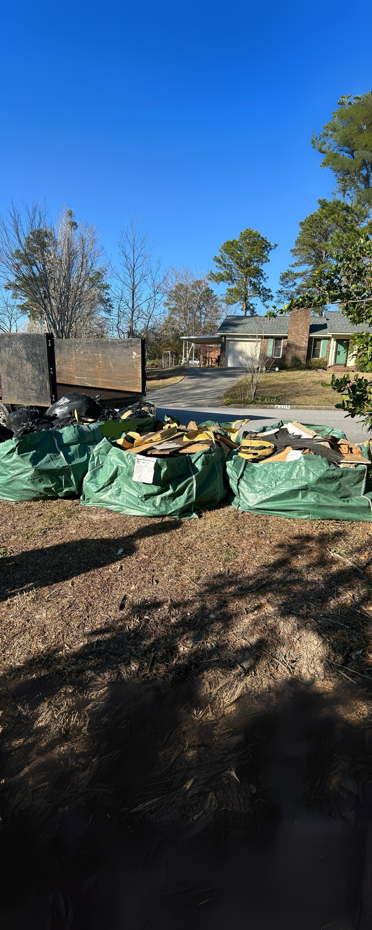 Junk Empire hauling service with large green debris bags filled with construction waste ready for pickup.