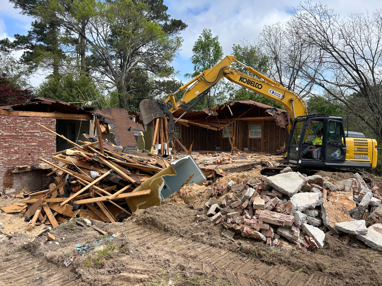 Junk Empire demolition project with an excavator tearing down a house and debris piled on-site.