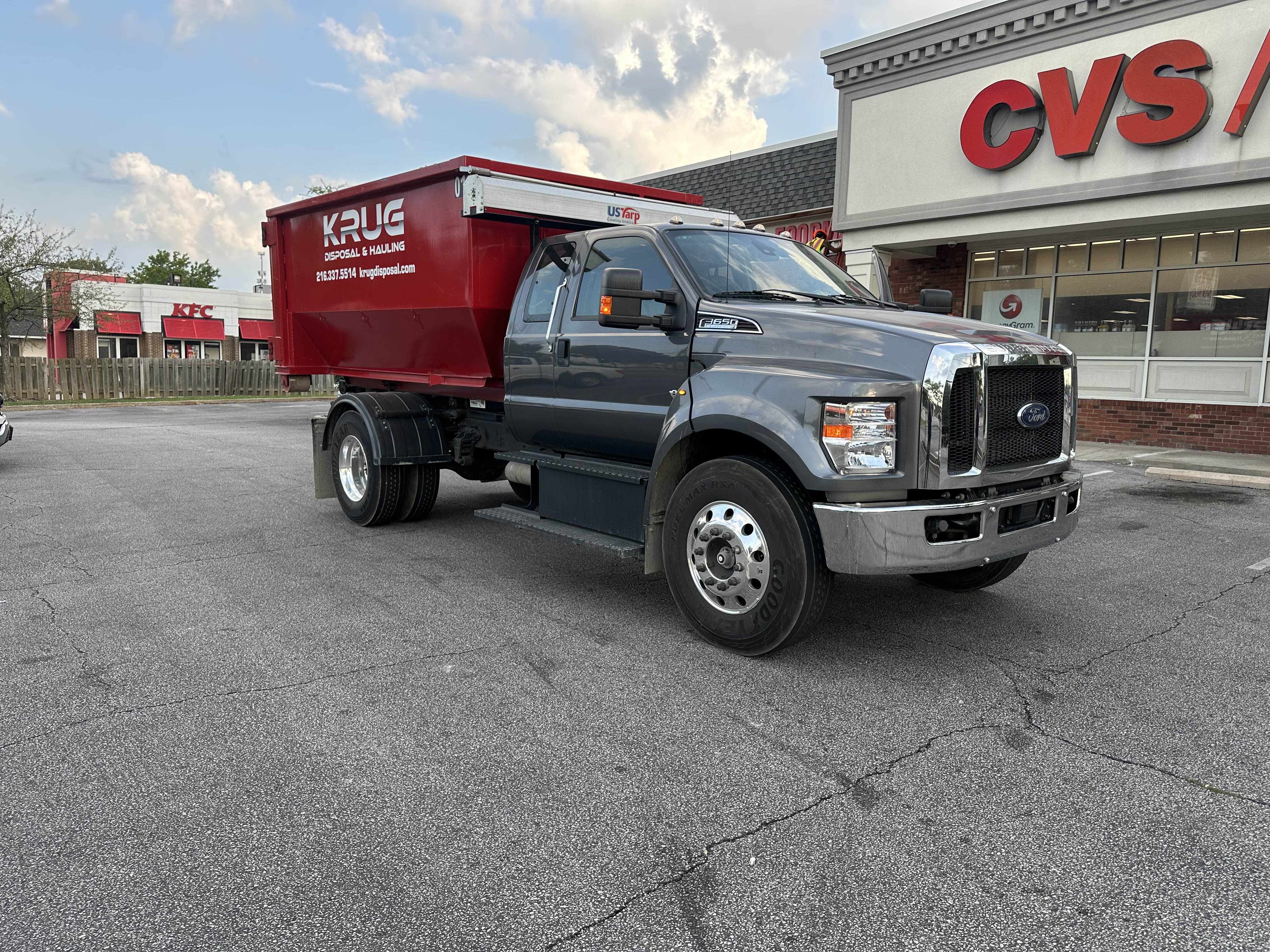 Krug Disposal & Hauling roll-off dumpster truck parked outside CVS