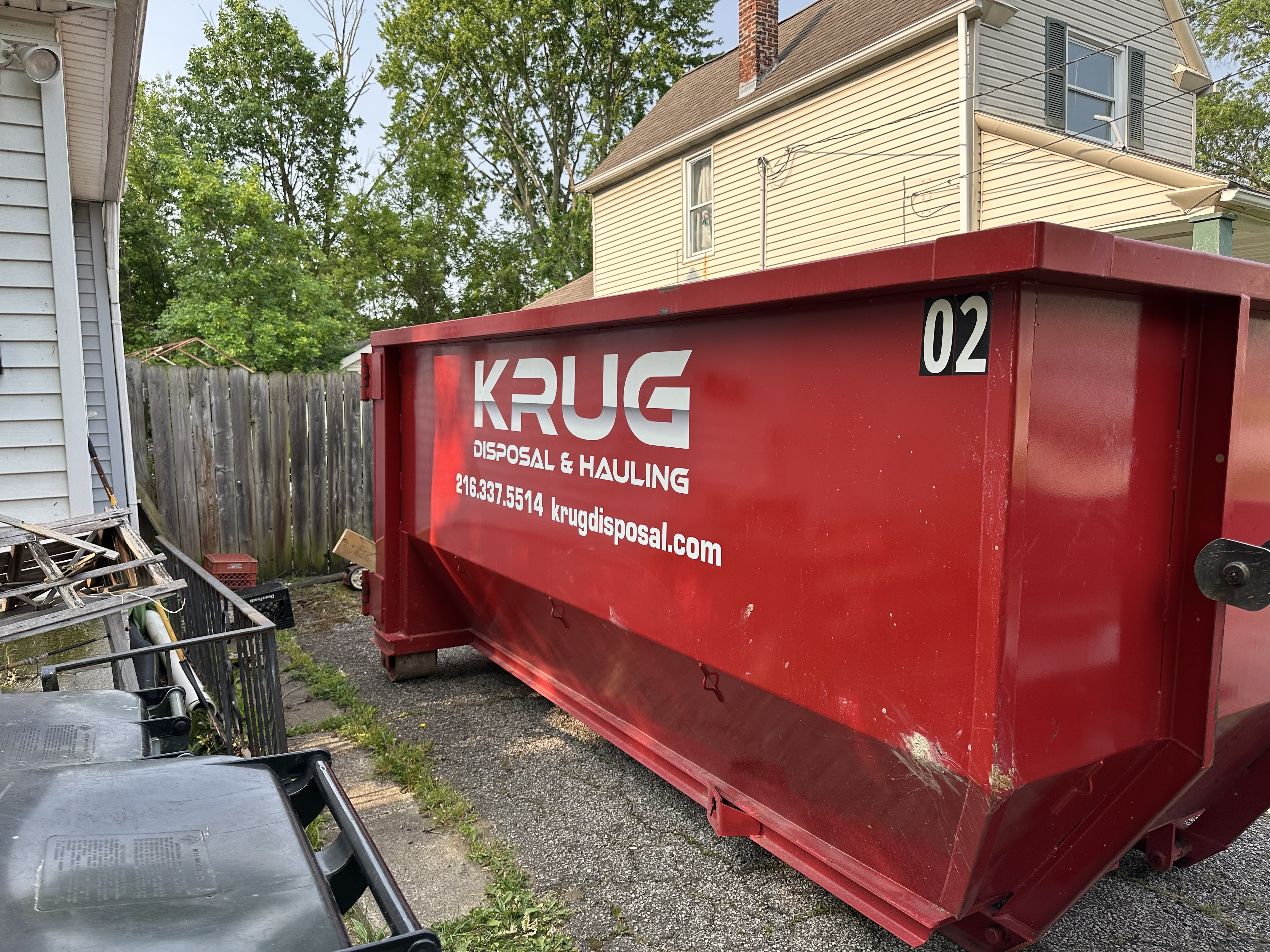 Krug Disposal & Hauling truck transporting a roll-off dumpster