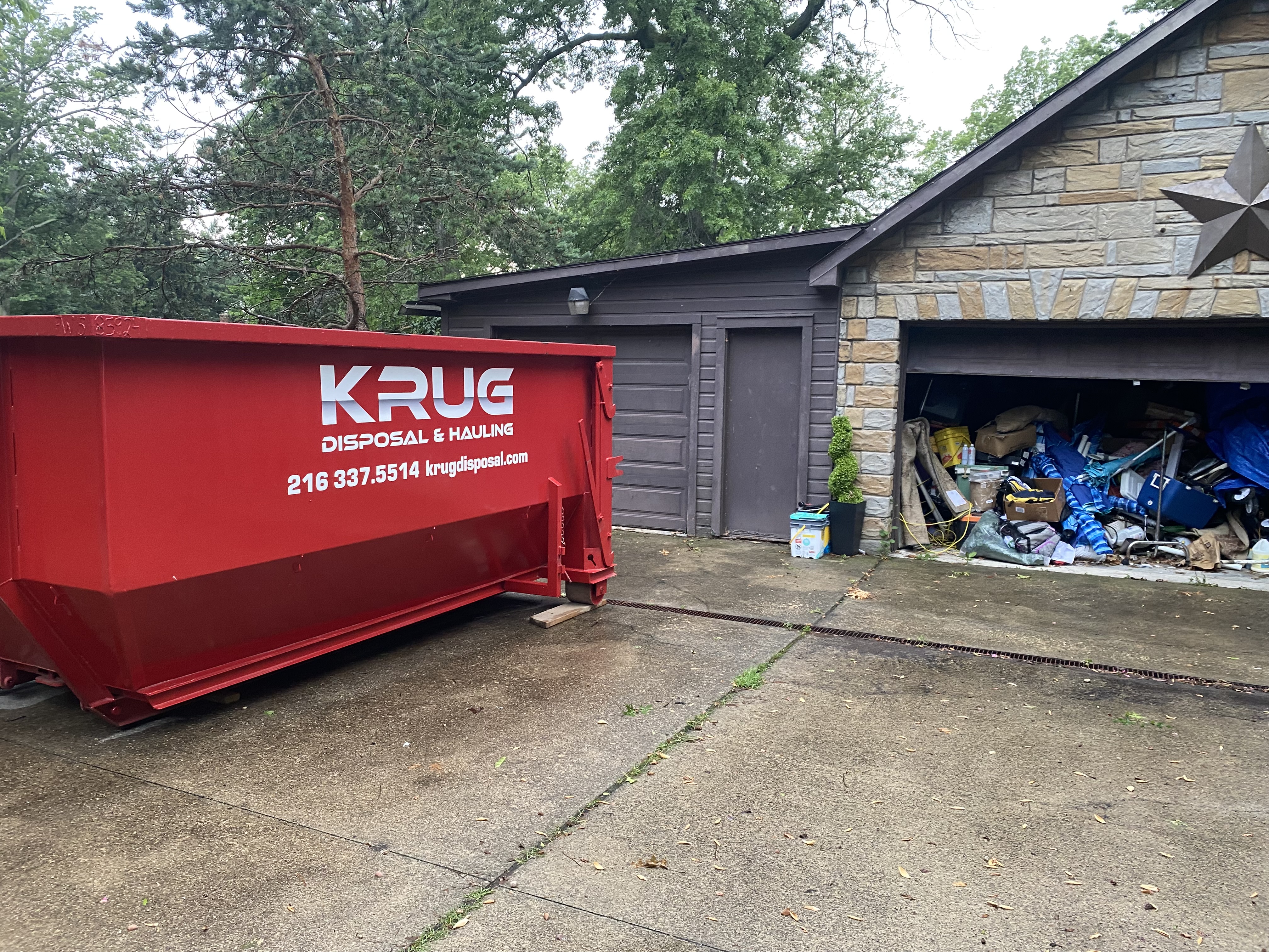 Krug Disposal & Hauling truck transporting a roll-off dumpster