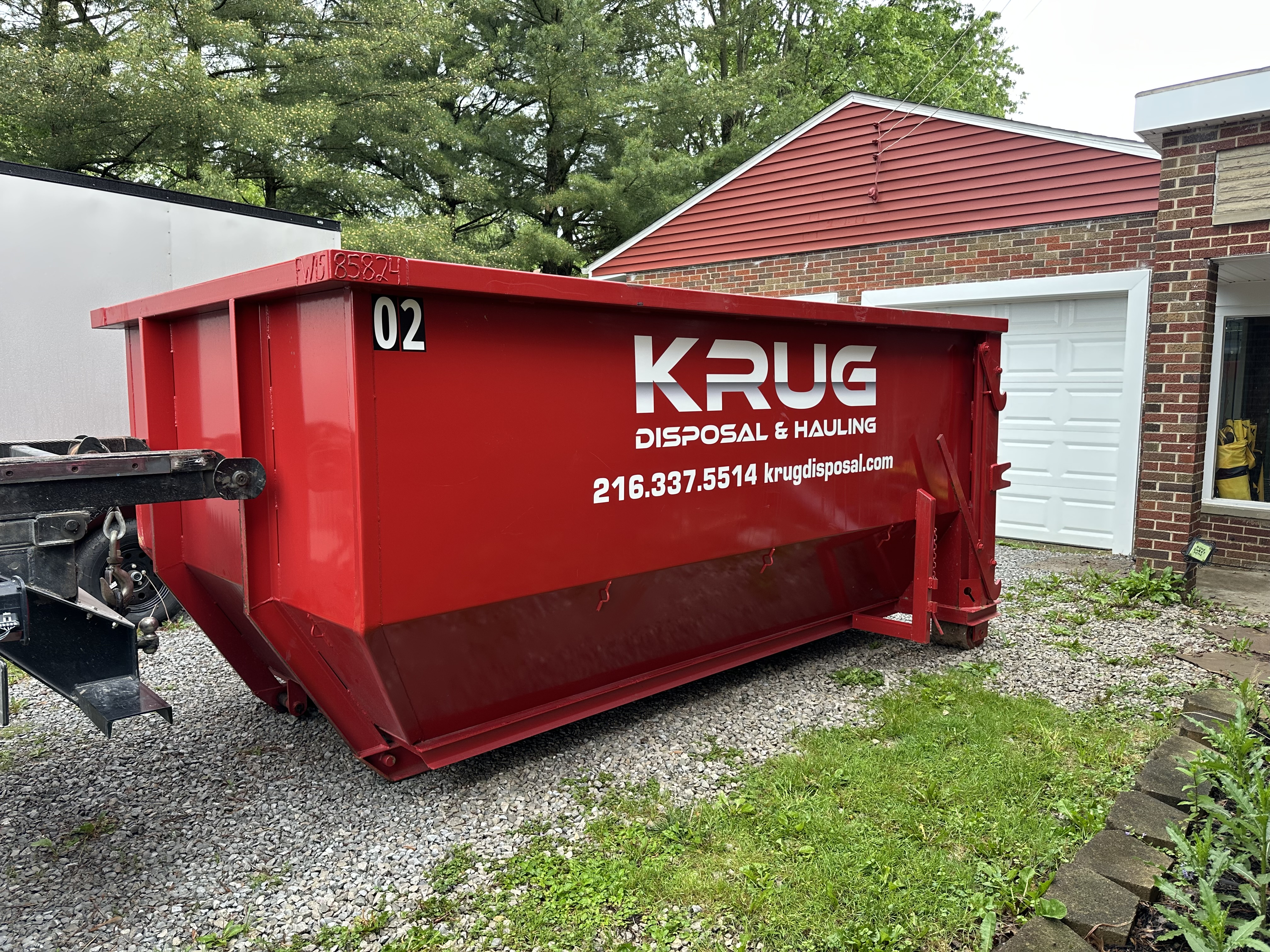 Krug Disposal & Hauling truck transporting a roll-off dumpster