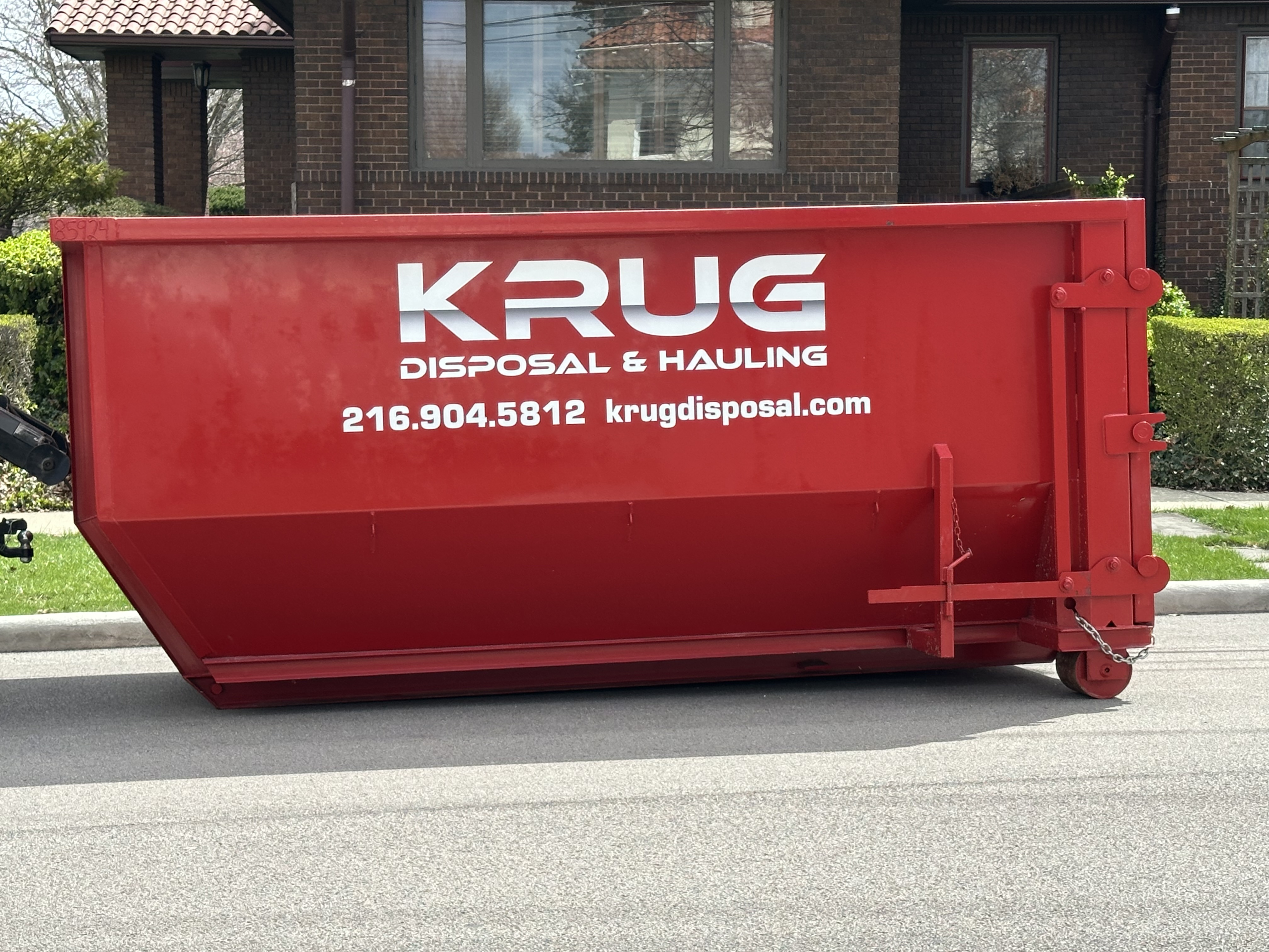 Krug Disposal & Hauling truck transporting a roll-off dumpster