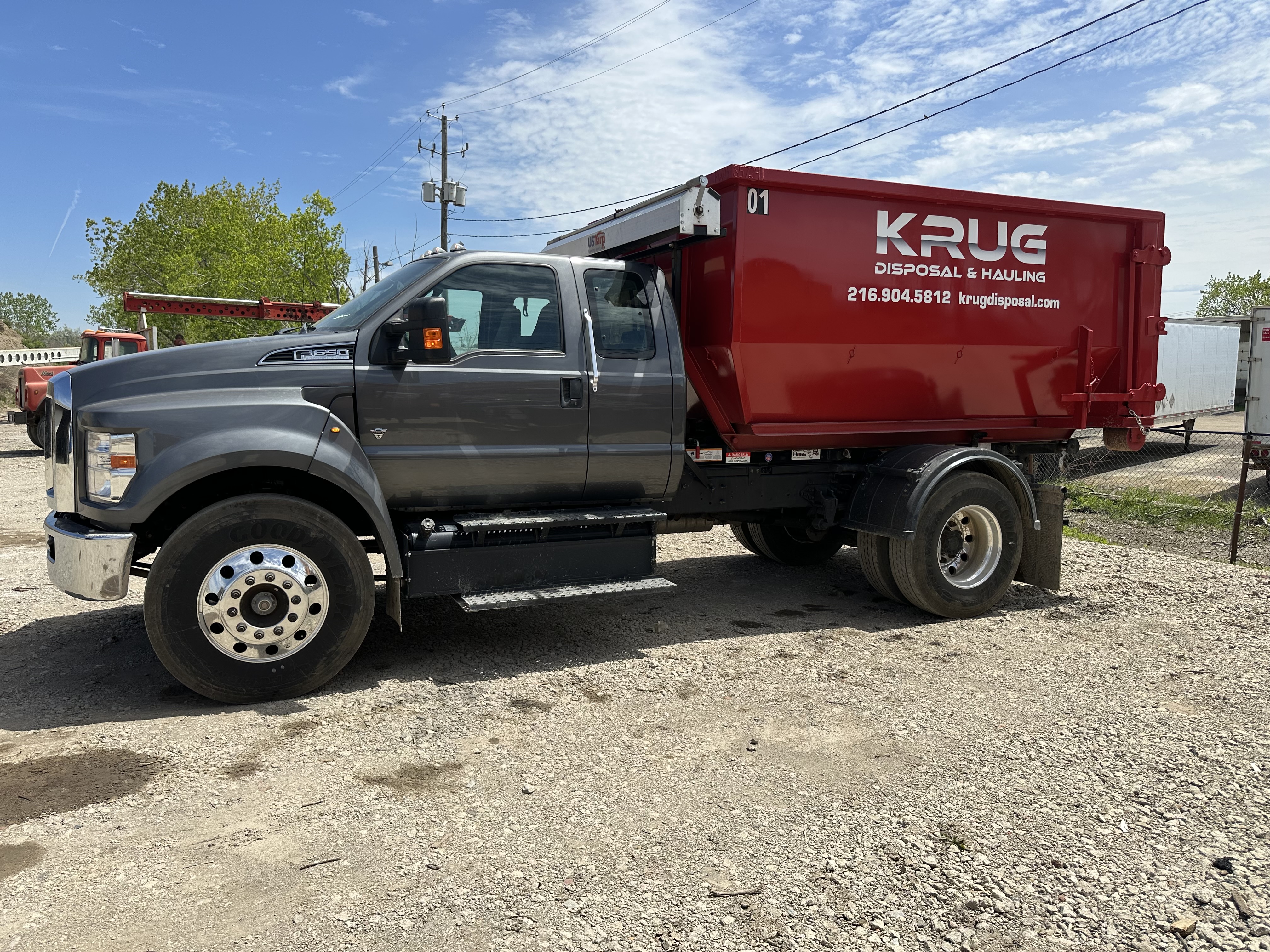 Krug Disposal & Hauling truck transporting a roll-off dumpster