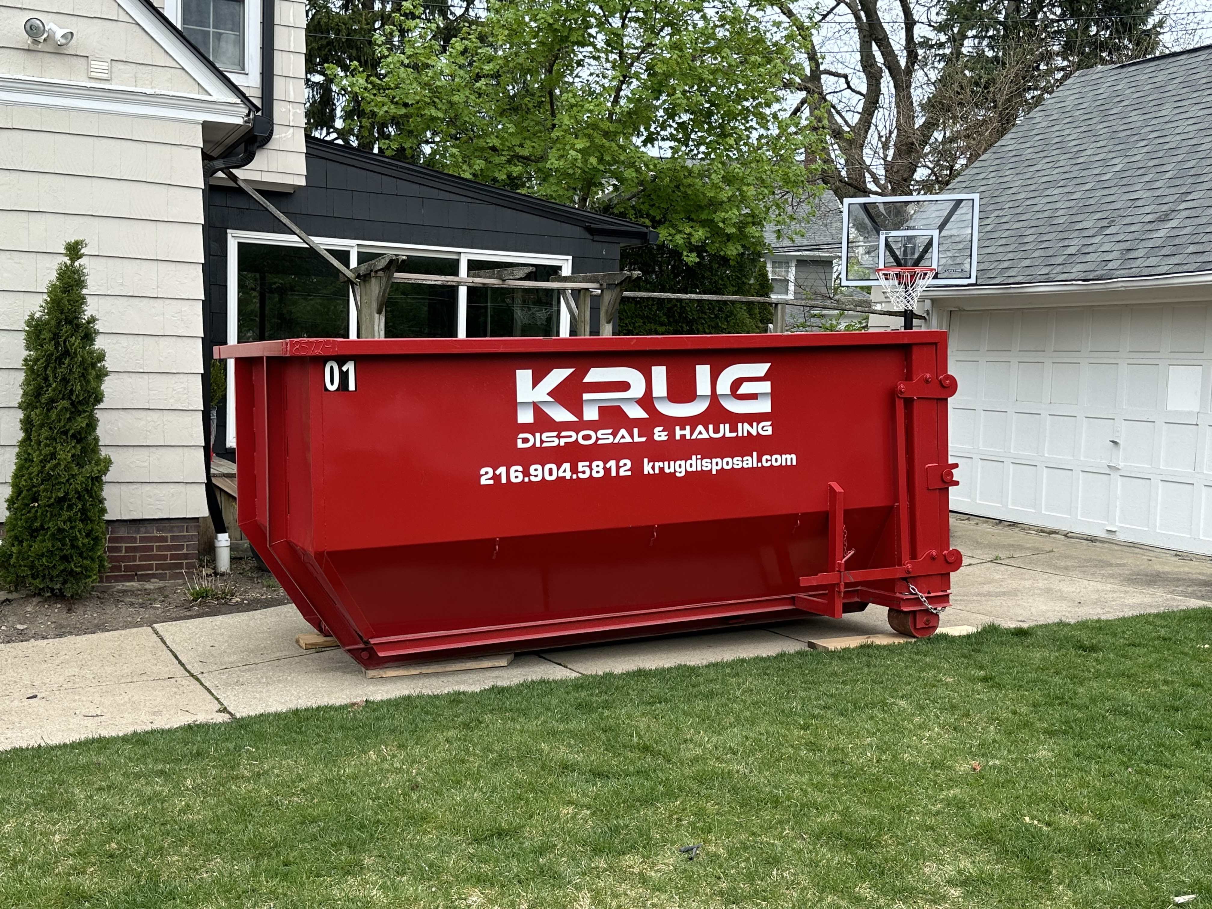 Krug Disposal & Hauling truck transporting a roll-off dumpster