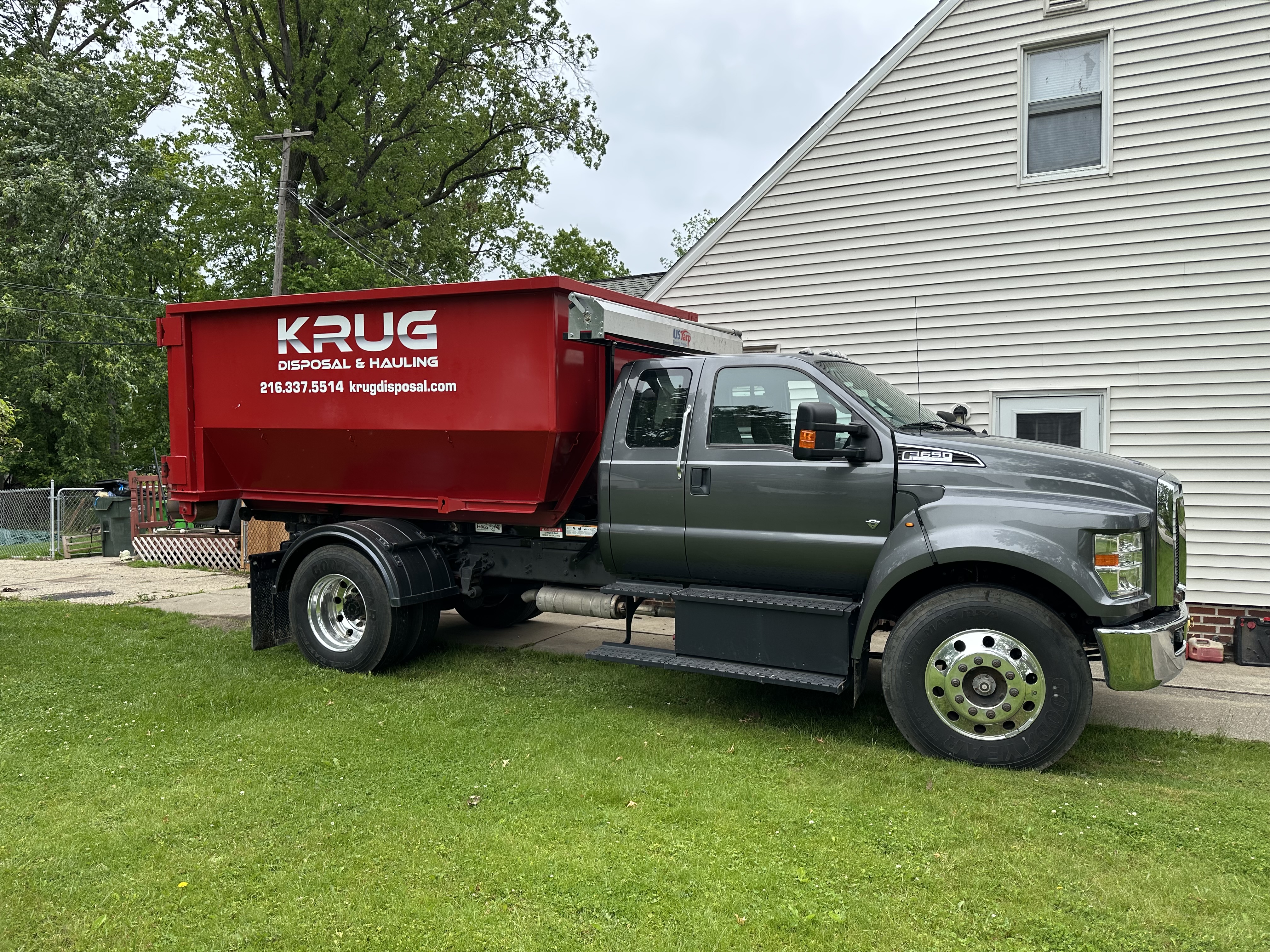 Krug Disposal & Hauling truck transporting a roll-off dumpster