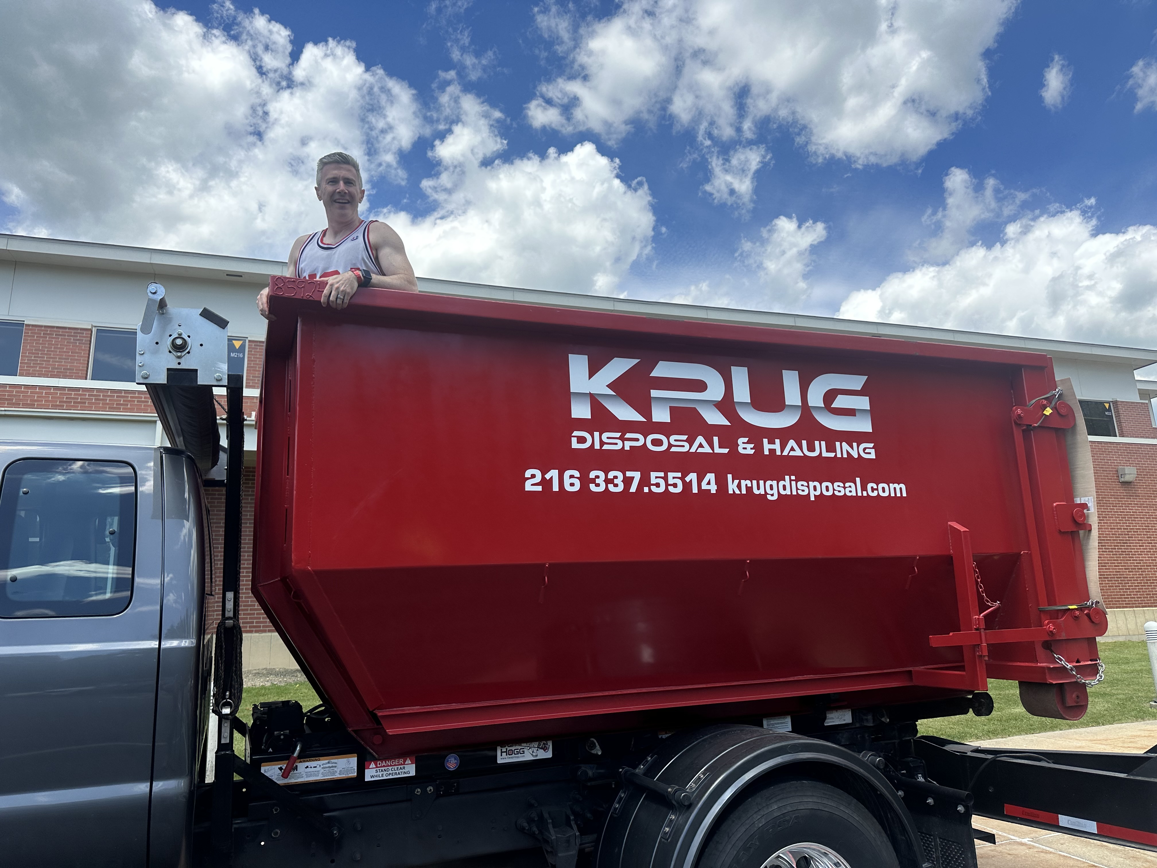 Krug Disposal & Hauling truck transporting a roll-off dumpster