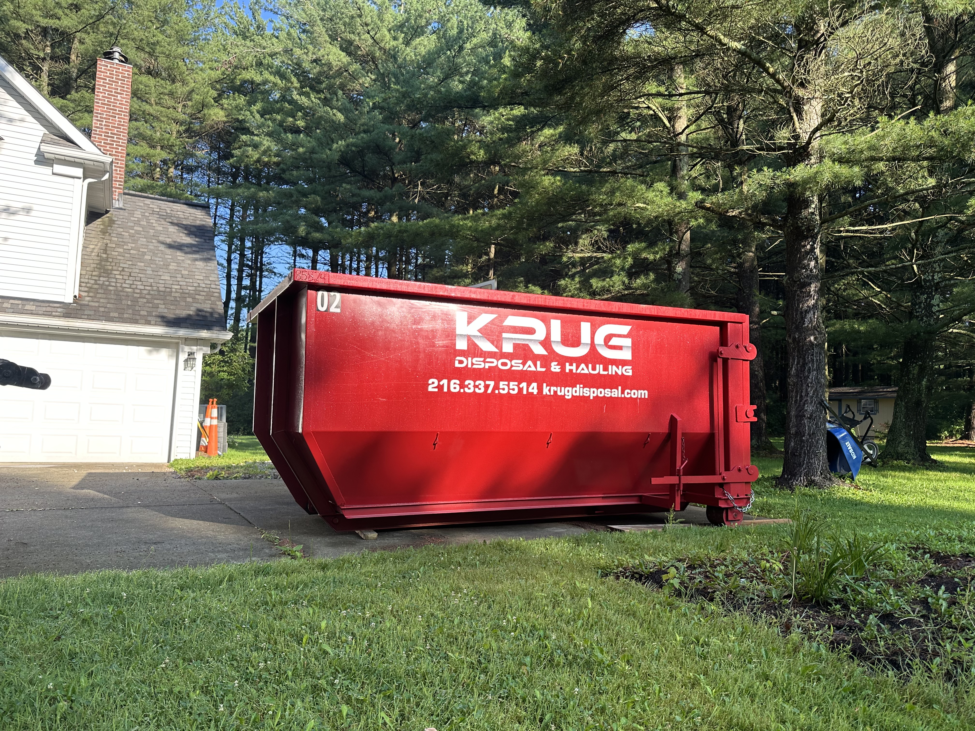 Krug Disposal & Hauling truck transporting a roll-off dumpster