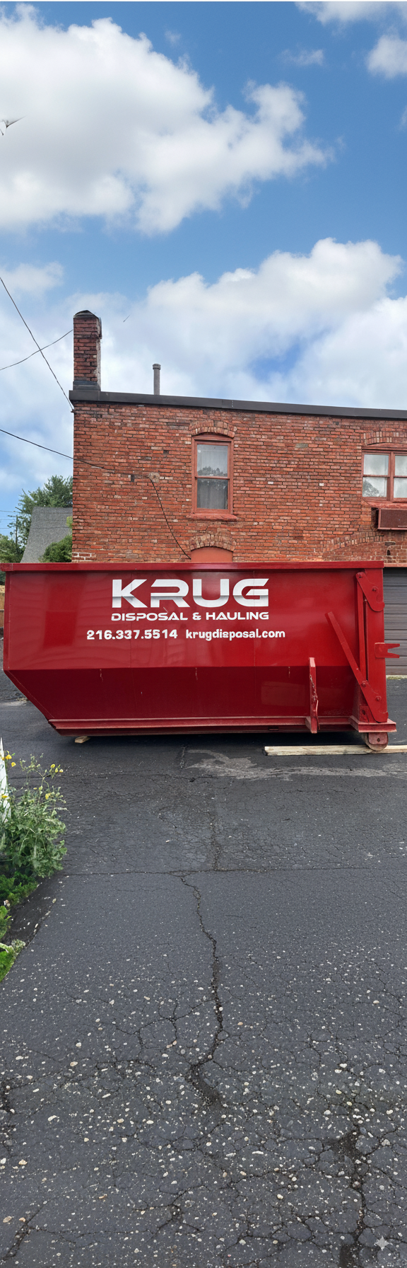 Red commercial dumpster from Krug Disposal in a residential driveway.
