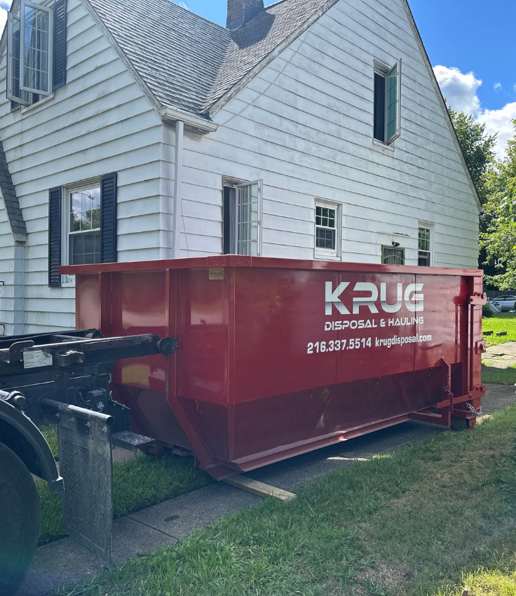 Krug Disposal red dumpster being delivered to a house.