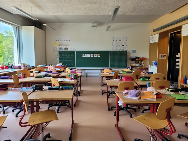 Classroom with desks and students attending a lesson Classroom with desks and students attending a lesson