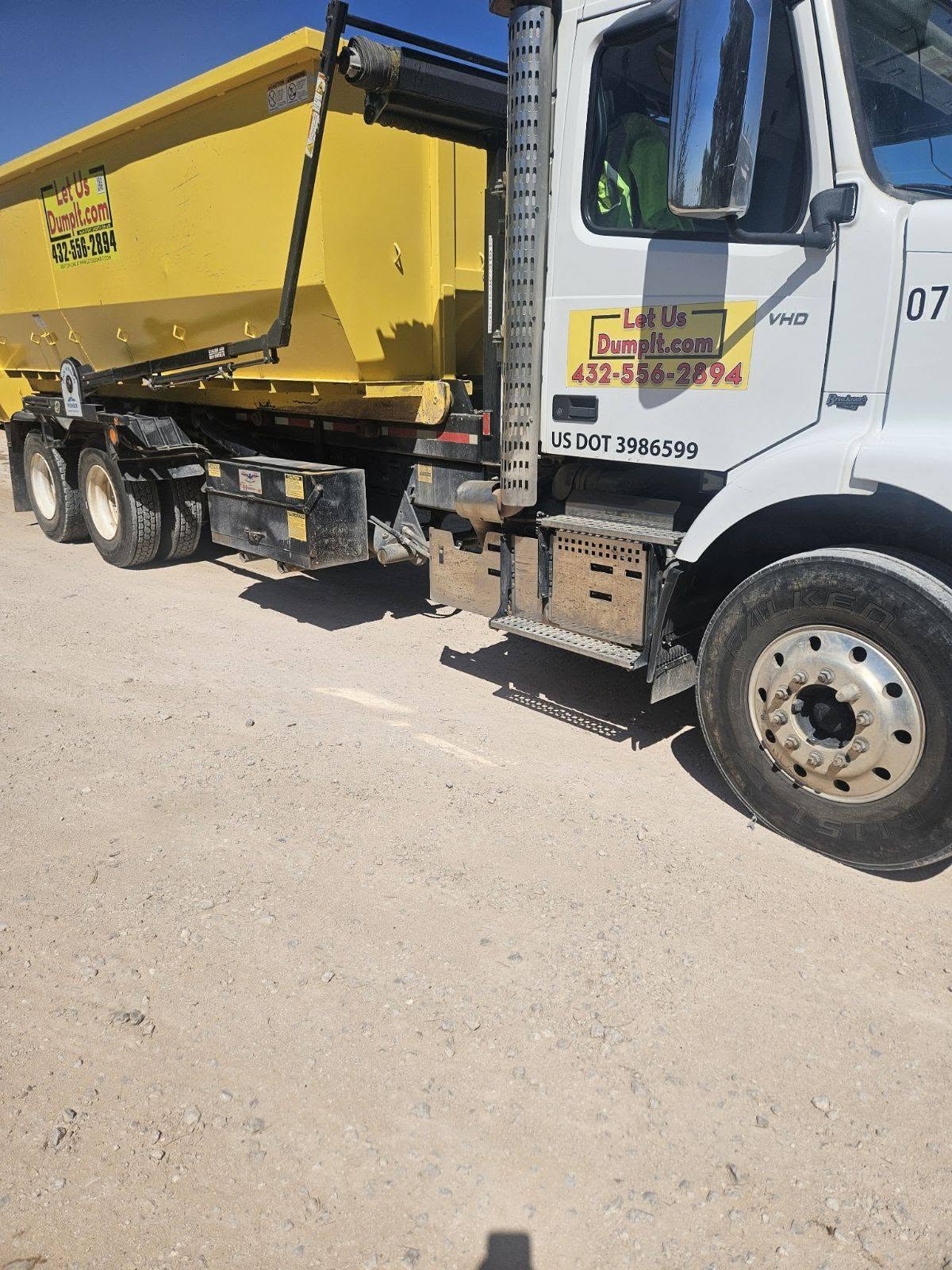 Ricky Hickey, owner of Let Us Dump It, standing with a roll-off dumpster truck in Midland TX