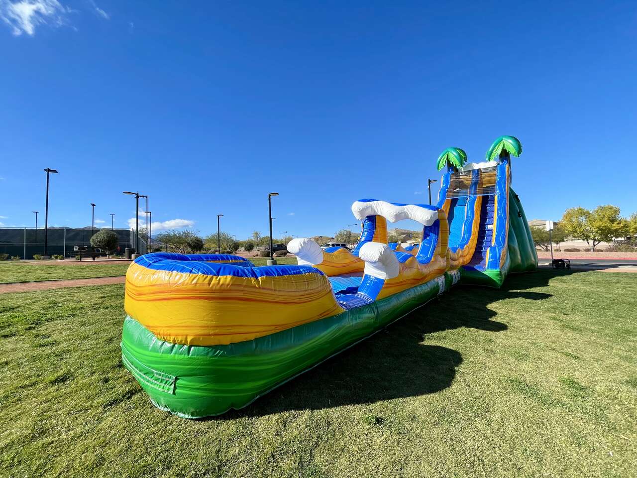 Inflatable water slide with palm trees in a park setting, showcasing vibrant colors and fun design, ideal for events and parties in Las Vegas Inflatable water slide with palm trees in a park setting, showcasing vibrant colors and fun design, ideal for events and parties in Las Vegas