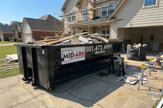 Construction dumpster on a job site for debris removal from Mid-Ark Dumpsters LLC