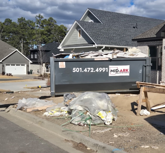 Roll-off dumpster on a residential construction site for debris cleanup with Mid-Ark Dumpsters LLC