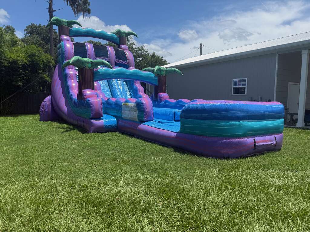Purple and teal inflatable water slide set up on grass for a local event