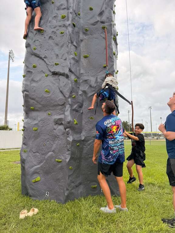 Child climbing the mobile rock wall with event staff nearby