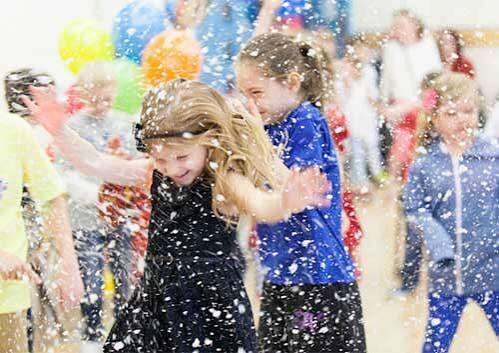 Children playing in artificial snow from a professional snow machine rental in Orlando and Central Florida
