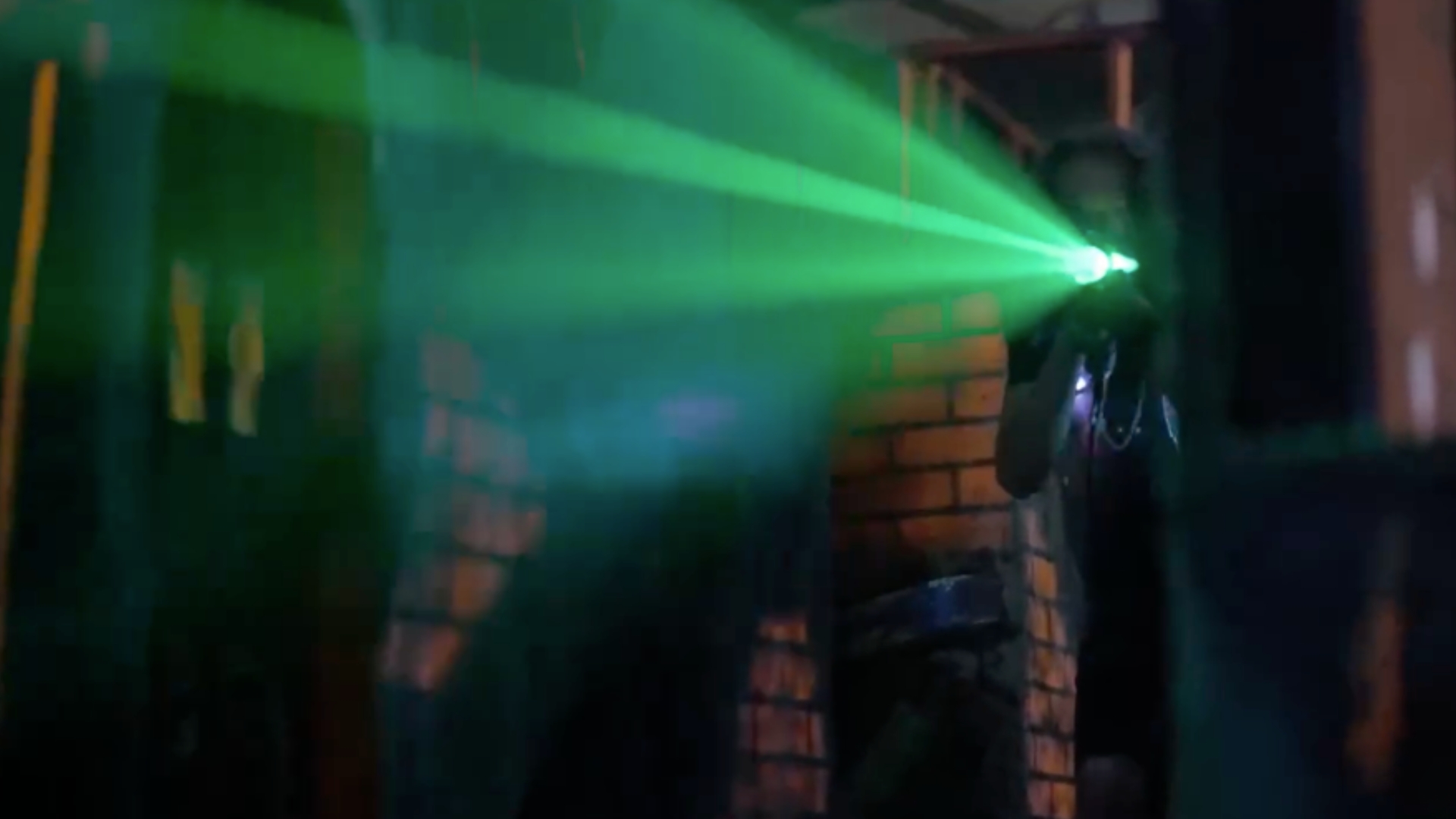 Kids mid-game inside Mission Laser 757 — fog filling the multi-level arena, vests glowing in neon green