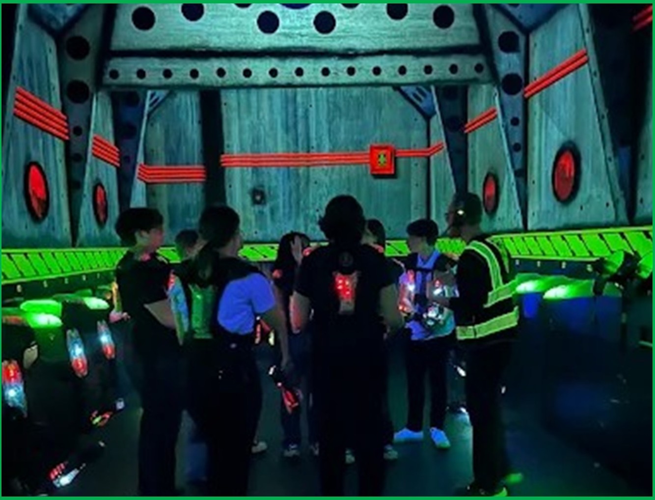kids mid-game in the haze with vests glowing, multi-level visible - Mission Laser Charlotte