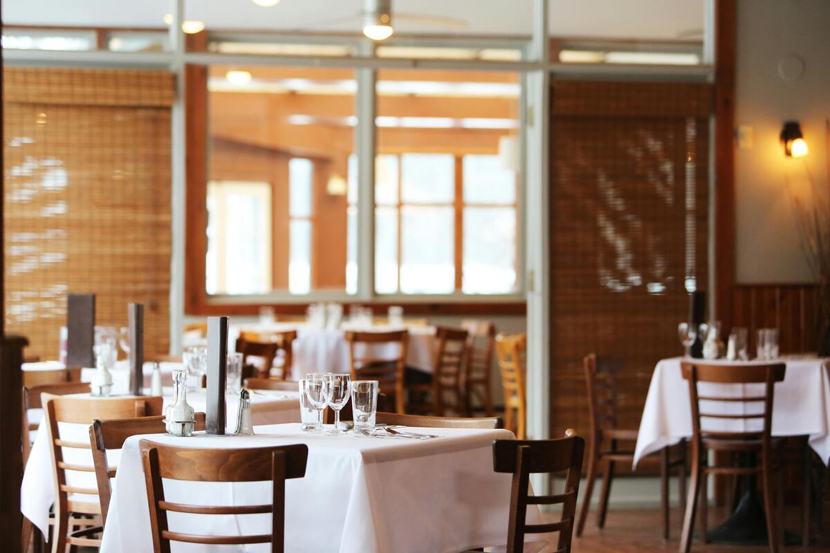 Elegant restaurant with wooden chairs and white tablecloths.