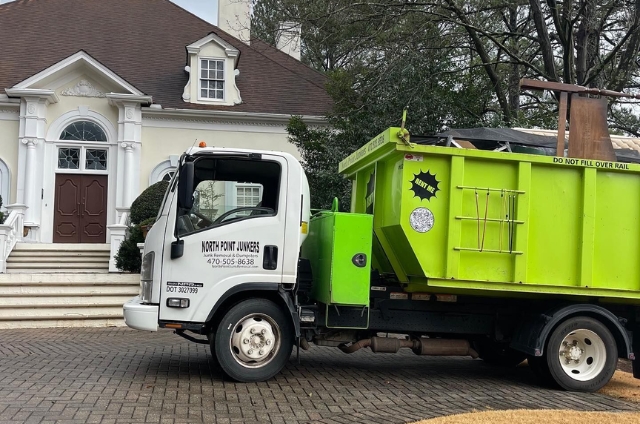 North Point Dumpsters delivery truck with a lime-green roll-off container parked outside a residential home