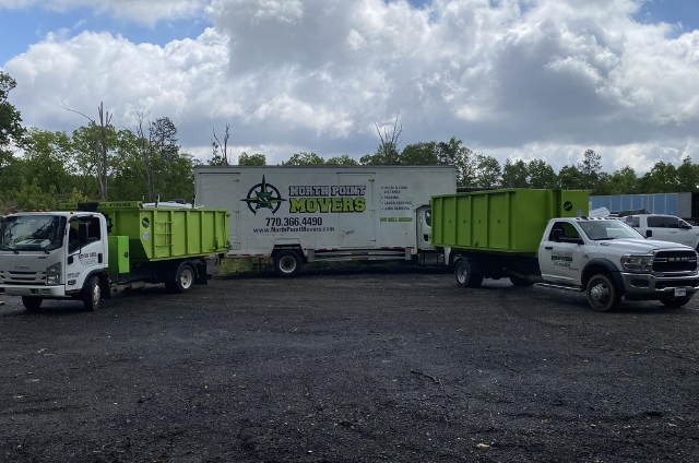 Fleet of roll-off containers and trucks from North Point Dumpsters parked at an industrial facility