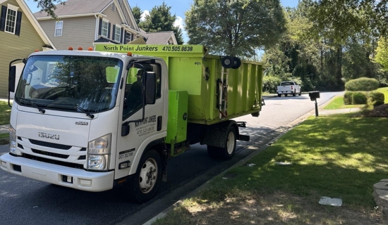 North Point Dumpsters truck hauling a large lime-green roll-off container through a suburban neighborhood