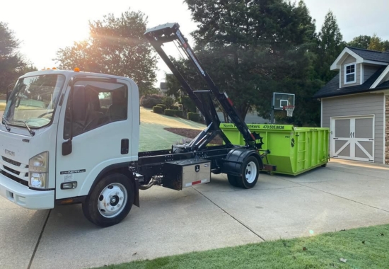 North Point Dumpsters truck unloading a lime-green roll-off container in a suburban driveway