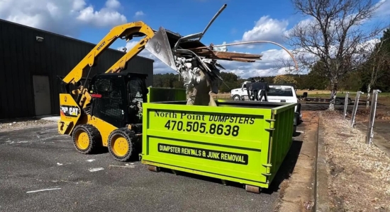 CAT skid steer loading debris into a North Point Dumpsters roll-off container at a commercial property