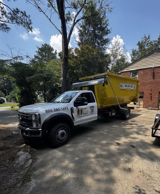 Junk Dump Store Company truck dropping off a dumpster in a residential driveway