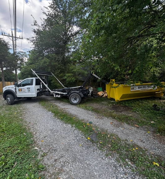 Junk Dump Store Company truck placing a dumpster on a rural gravel driveway