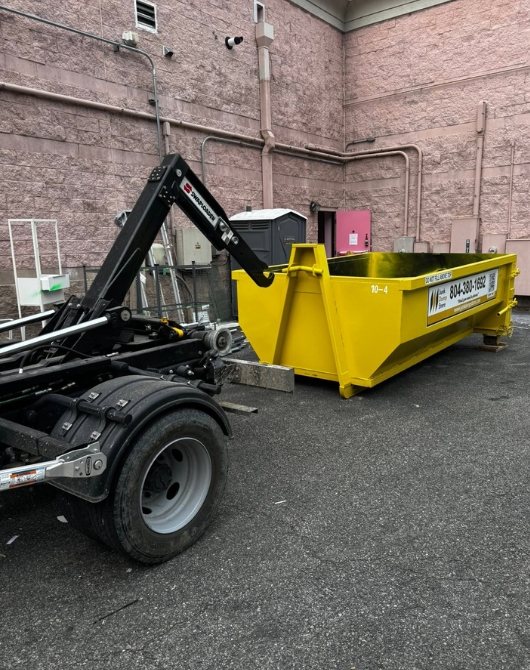 Junk Dump Store Company unloading a roll-off dumpster at a commercial site