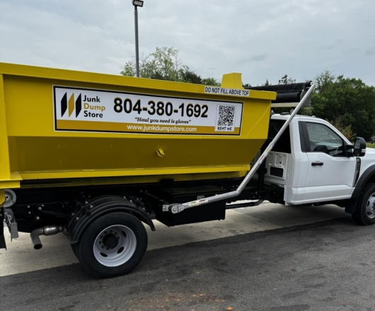 Yellow roll-off dumpster on a Junk Dump Store Company hooklift truck