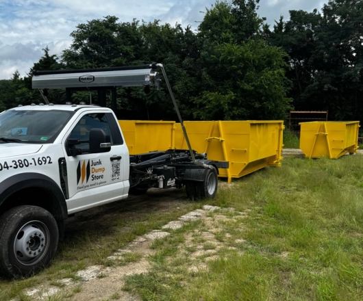 Junk Dump Store Company truck delivering a yellow roll-off dumpster