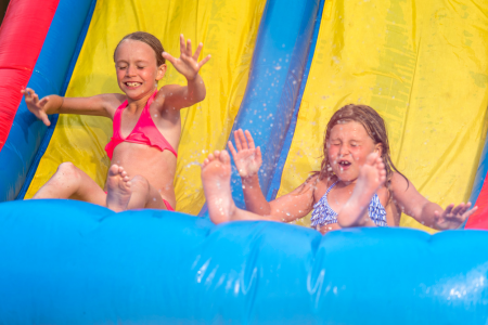 Kids splashing and sliding down a colorful inflatable water slide