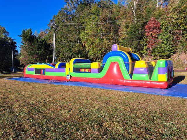 60-foot rainbow rush inflatable obstacle course set up outdoors for a party or event in Easley, SC, featuring tunnels, climbing elements, and bright colors ideal for school events and festivals.