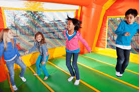 Kids jumping inside a colorful bounce house at an end-of-school party rental in the Greenville, SC area.