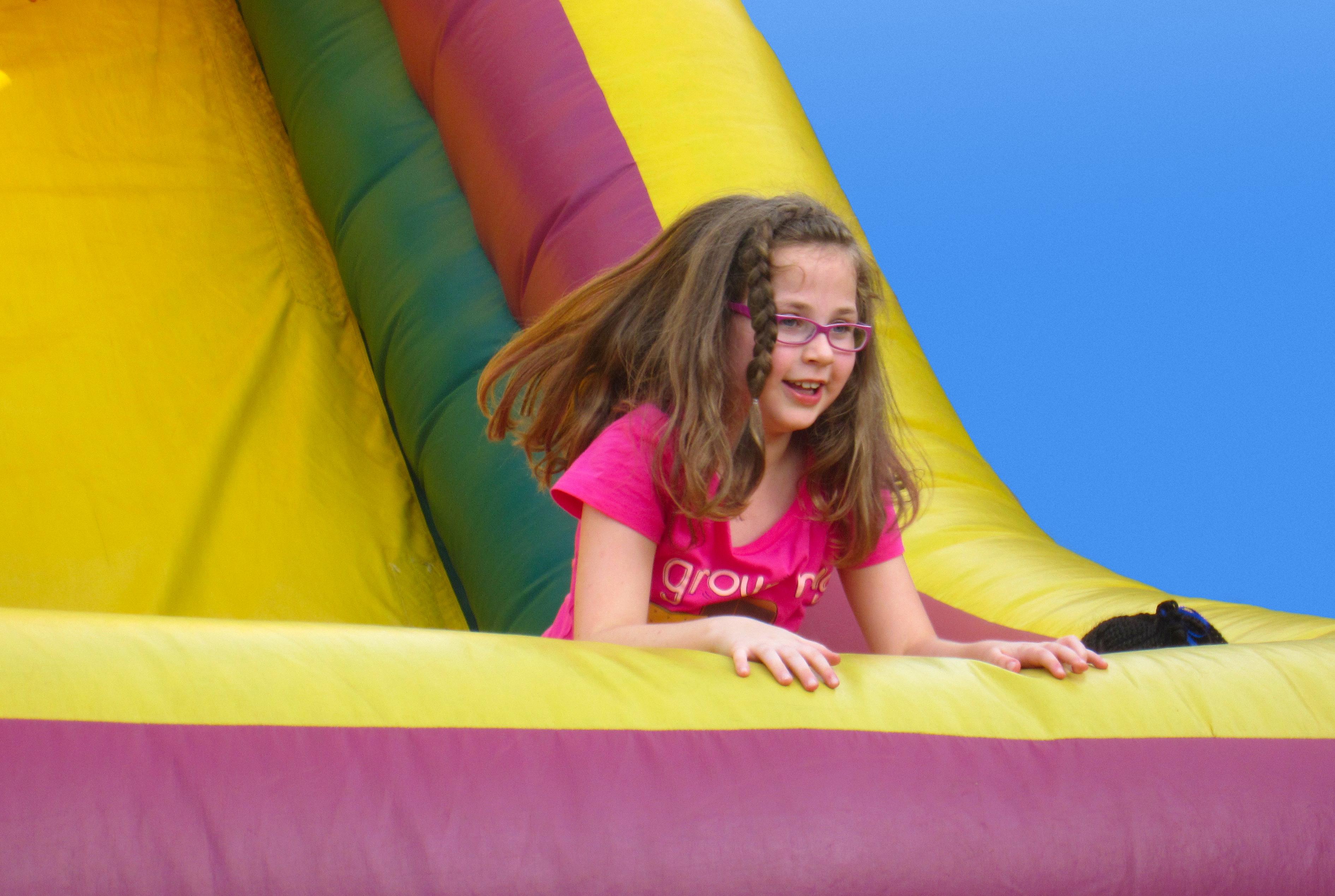 Alt Text: Smiling girl sliding down a colorful inflatable from bounce house rentals in Taylors, SC Alt Text: Smiling girl sliding down a colorful inflatable from bounce house rentals in Taylors, SC