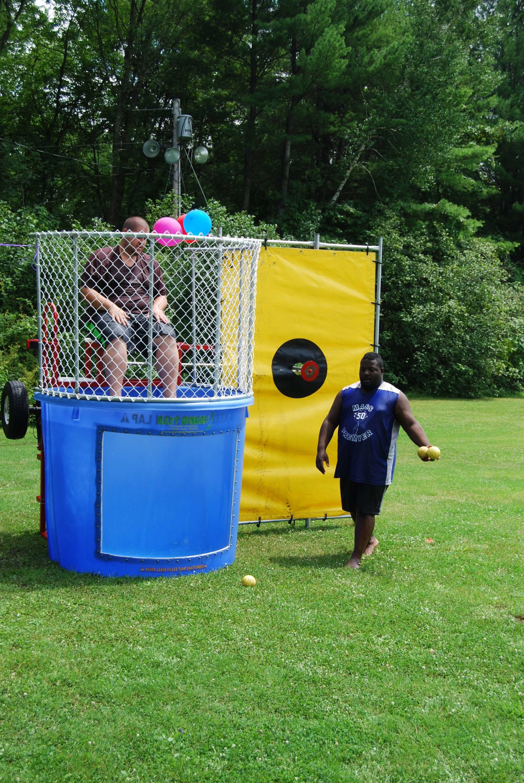 Dunk tank rental in Wade Hampton SC set up outdoors with participant seated in cage above water tank