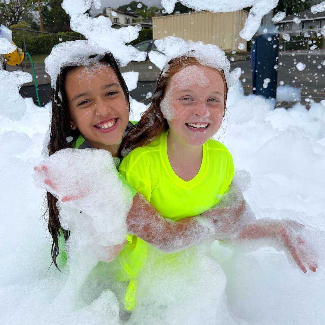 Two young girls in swimsuits smiling and covered in bubbles during a foam party in Parker, SC. Two young girls in swimsuits smiling and covered in bubbles during a foam party in Parker, SC.