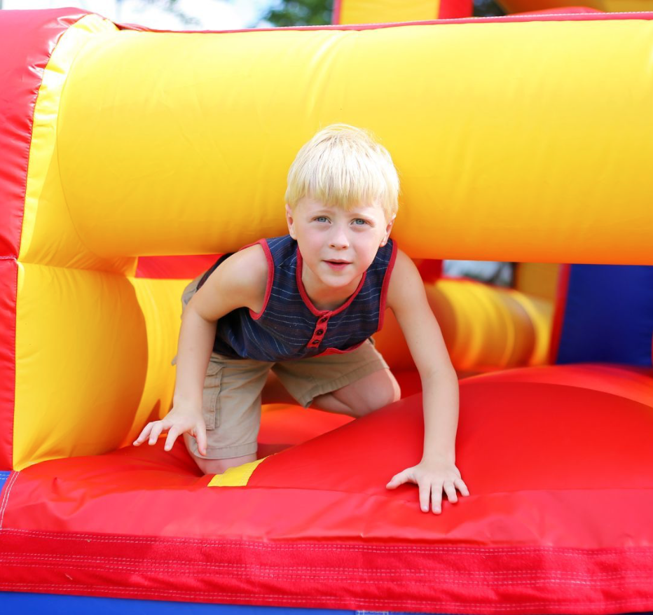 Young boy crawling through a bright inflatable obstacle at a family event in Greenville, SC