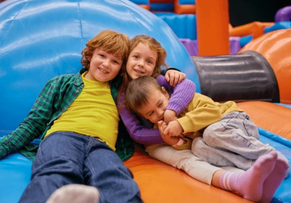 Three children relaxing and smiling inside an inflatable play area at a backyard party in Greenville, SC